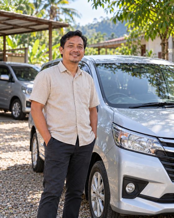 Pemilik armada berdiri di samping mobil travelnya